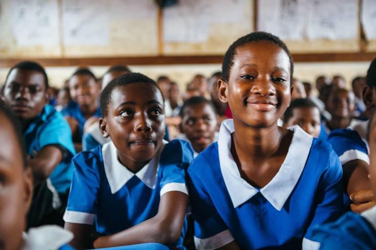 Schoolgirls in uniform smiling in a classroom